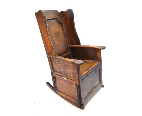 A 17th /18th century jointed oak lambing chair, the wing back with fielded back panel over shaped flat arms, a panelled box s