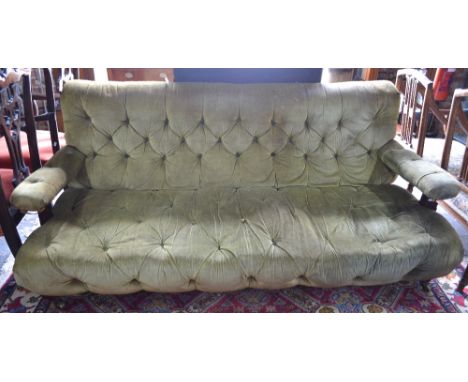 A Victorian sofa attributed to Howard & Son, the green velvet button upholstered back over open arms and a deep buttoned seat