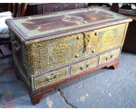 A 19th century Zanzibar chest, the heavily brass mounted hardwood trunk with hinged top over three drawers, raised on later s