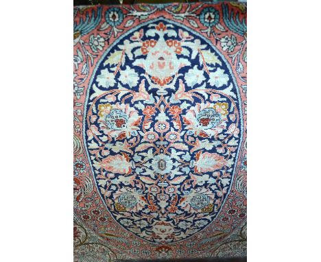 A fine Persian silk rug, Tehran circa 1960's, the ovoid centre panel with floral design on blue, pink and natural ground, 1.5