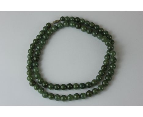 A jade bead necklace strung with uniform beads on a screwed barrel clasp, the beads 9.5mm