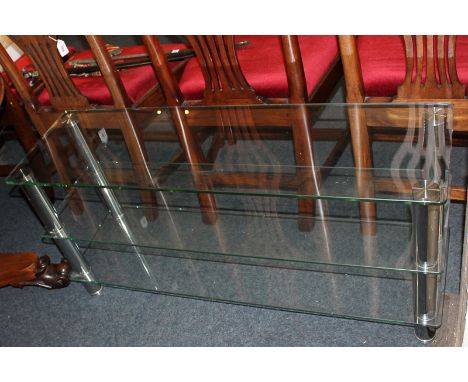 A plate glass three-tier shelf with chrome supports, 110cm by 34cm