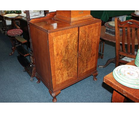 A figured walnut cabinet with one shelf enclosed by two banded doors, on short cabriole legs, 77cm