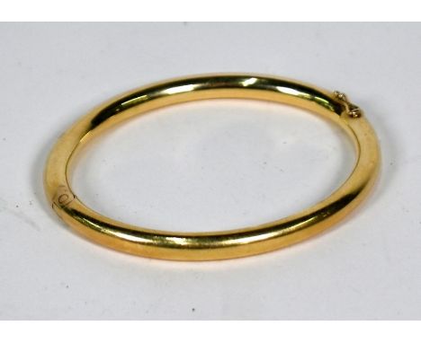 A yellow metal oval half-hinged plain hollow bangle with concealed snap, stamped 585, approx 21.9g, 6.5 x 5.5 cm internal&nbs