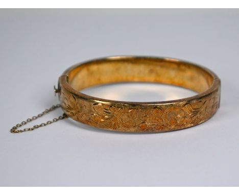 A 9ct yellow gold half-hinged oval bangle with foliate engraved decoration, with safety chain attached, approx 19.3g&nbsp;Goo