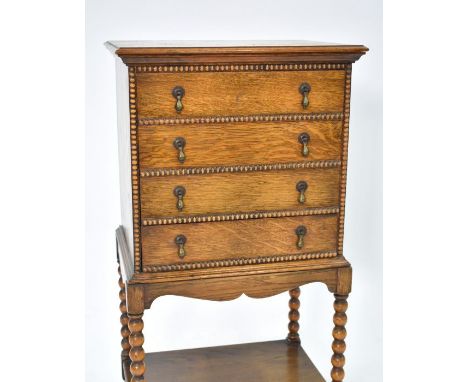 An oak four drawer music cabinet, with bobbin turned supports to an open shelf, 51 cm x 38 cm x 93 cm h (internal dimensions 