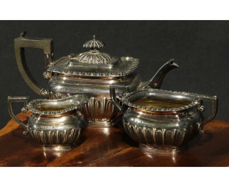 An Edwardian silver three piece half-fluted bachelor's tea service, comprising teapot, milk jug and sugar basin, Birmingham 1