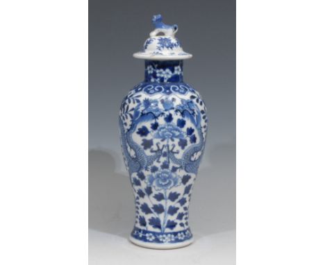 A Chinese ovoid vase and cover, painted in tones of underglaze blue with dragons amongst flowers and foliage, temple lion fin