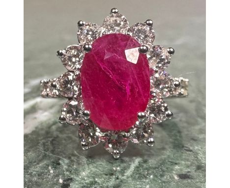 A certified ruby and diamond ring, central purplish red mixed cut oval ruby, 3.08ct, surrounded by a collar of twelve round b