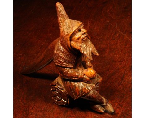 Nutcrackers - a Black Forest novelty table top lever-action nut cracker, carved as a bearded gnome seated on a log, 16.5cm hi