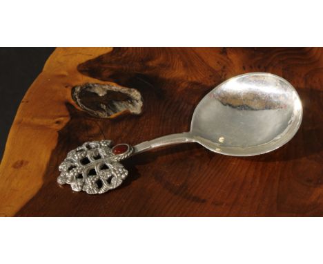 An Arts and Crafts silver caddy spoon, planished rat tail bowl, the terminal as a stylised fruiting tree, set with an oval ca