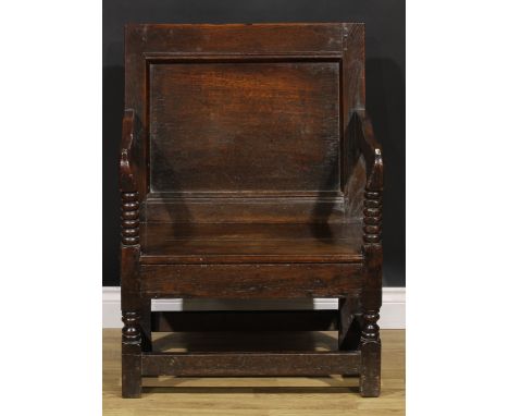 An 18th century wainscote armchair, of wide proportions, rectangular panel back, shaped arms on bobbin-turned supports, board