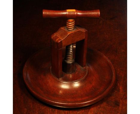 Nutcrackers - a 19th century mahogany table top screw-action nut cracker, corkscrew form handle, broad dished circular base, 