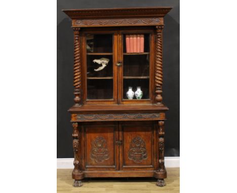 A 19th century Colonial teak library bookcase, outswept dentil cornice with foliate swag capital above a pair of glazed doors