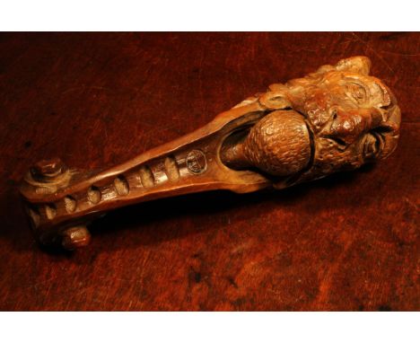 Nutcrackers - a late 18th century walnut lever-action nut cracker, naively carved as the head of a lion, 25cm long, c.1800