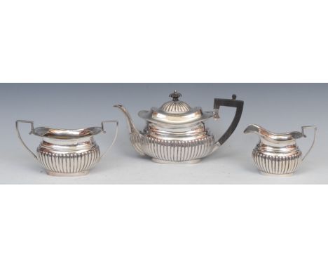 A Victorian silver three piece half-fluted boat shaped tea service, comprising teapot, milk jug and sugar basin, angular scro