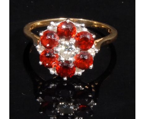 A diamond and garnet floral cluster ring, central brilliant cut diamond approx 0.25ct, surrounded by six orangy red garnets, 