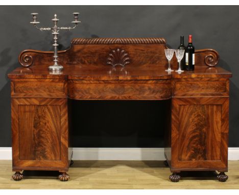 A George IV mahogany twin pedestal sideboard or serving table, shaped half-gallery with gadrooned capital centred by a stylis