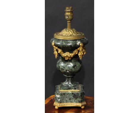 An early 20th century gilt metal mounted verde antico marble campana table lamp, applied with flowering swags, canted square 