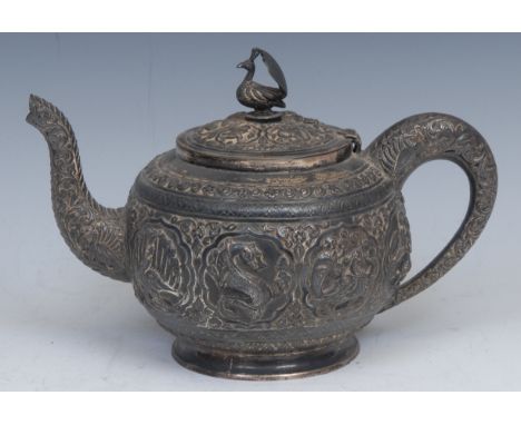 An Indian silver coloured metal teapot, chased with deities, animals, lotus and scrolls, hinged cover with peacock finial, 20