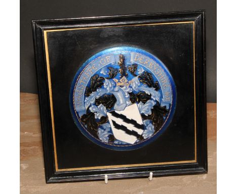 An Arts &amp; Crafts enamel armorial convex plaque or boss, painted in polychrome and gilt with the arms of Wagstaffe of Derb