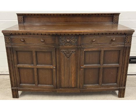 A vintage dark wood Old Charm style sideboard with carved detail and panelled doors. 2 cupboards to base, each with interior 