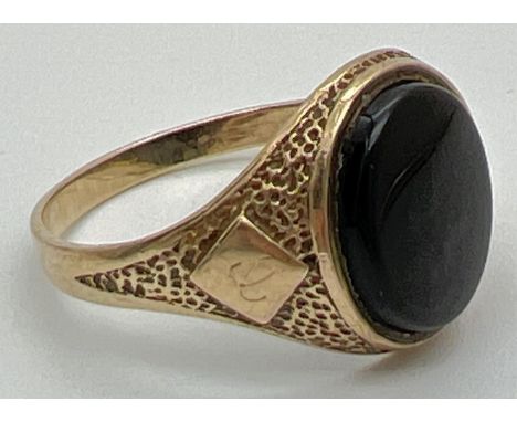 A mens 9ct gold vintage signet ring set with an oval black onyx stone. Pitted effect detail to shoulders with a small diamond