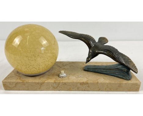An Art Deco design table lamp with spelter figure of a flying bird and spherical yellow glass shade. On a black marble base w