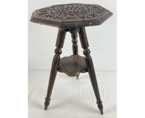 A small carved wooden 3 legged occasional table with small under shelf. Floral carving throughout top, legs and feet. Approx.