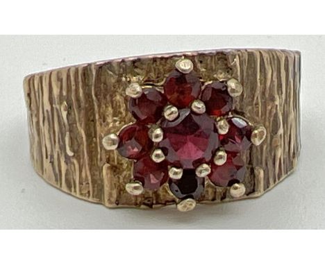 A vintage 9ct yellow gold ring with textured bark effect band set with a cluster of garnets in a floral setting. Fully hallma
