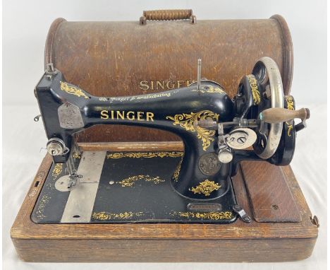 An antique wooden cased Singer sewing machine, black with gold floral decoration and shuttle bobbin. Complete with accessorie