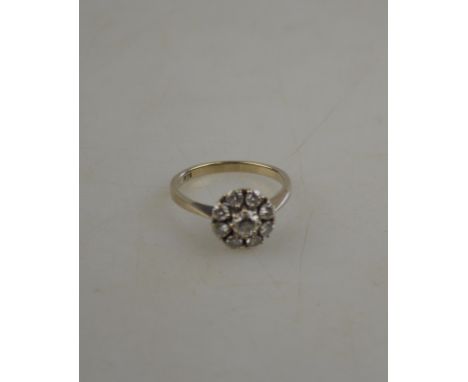 A diamond circular cluster ring set with nine brilliant cut diamonds, white metal set stamped 18k, claw set, size R 1/2