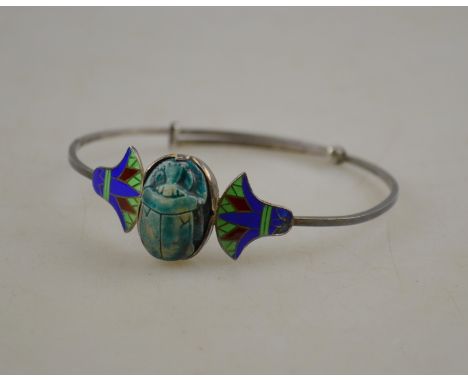 An Egyptian 90 grade bangle set with a faience scarab amulet flanked by enamelled stylised palm-fronds