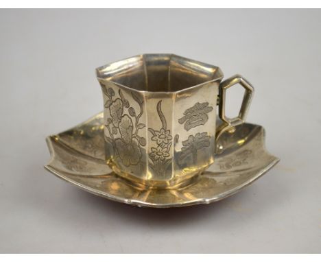 A Chinese white metal octagonal teacup and saucer incised with flowers and calligraphy, seal mark to base of each item, 5.4 o