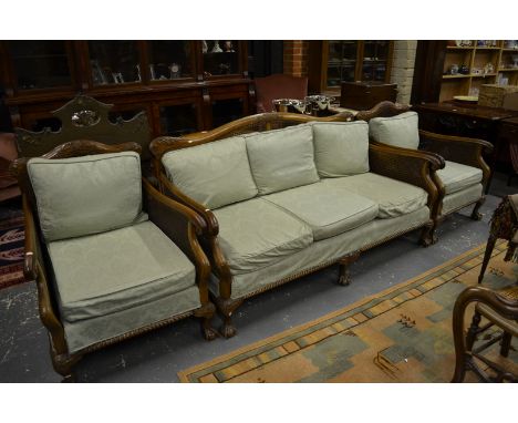 An Art Deco carved walnut framed bergere suite comprising a three seat sofa 