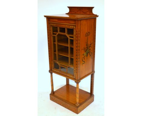 An Edwardian Sheraton Revival polychrome decorated satinwood cabinet having an astragal glazed door enclosing five shelves, r