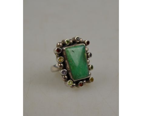 A large cocktail ring set with circular green stone having multi-coloured gems around including amethyst, peridot and garnet,