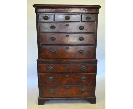 A George II feather-banded walnut oyster veneered chest on chest, having three short over three long drawers flanked by reede