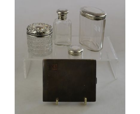 An engine-turned silver cigarette box, Birmingham 1929, to/w three silver-topped glass toilet jars and an unassociated top (b