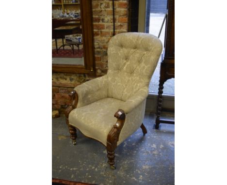 A Victorian mahogany framed button backed salon armchair, raised on turned front legs to ceramic castors