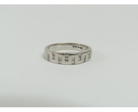 A platinum princess cut diamond band ring, the diamonds set in pairs into the band in a geometric pattern, marked to the insi