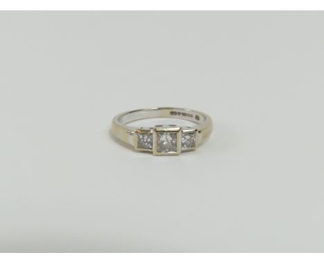 An 18ct white gold princess cut diamond three stone ring, the centre stone larger than the two flanking it, total diamond wei