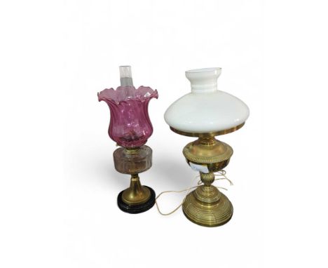 A decorative brass oil lamp with white glass shade together with brass and glass oil lamp with cranberry shade (2)