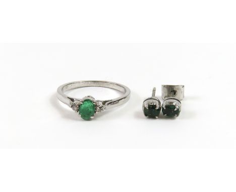 A pair of emerald single stone stud earrings, the oval shaped stones claw set in white metal, acid tests as approximately 9ct