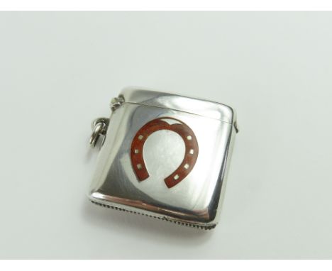 A silver vesta case, of smooth and curved form, with gold-coloured enamel horseshoe in the face. Made by Henry Matthews in Bi