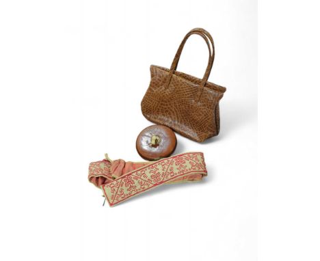 A vintage crocodile handbag along with an antique tape measure and a red-patterned sash