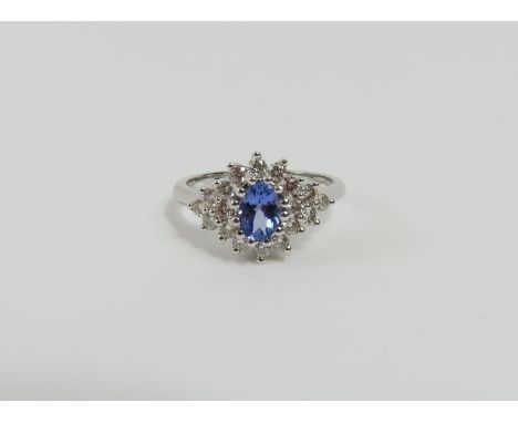 A 9ct white gold tanzanite and diamond cluster ring, the oval facetted tanzanite surrounded by a row of round brilliant cut d