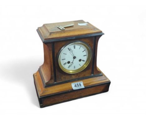 A 19th century veneered mantle clock with circular face; the interior accessed from the rear, with bell and clockwork inside.