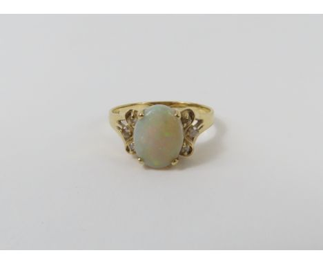 A white opal and diamond dress ring, the oval cabochon cut opal with three diamonds to each shoulder, marked '14k 585', finge