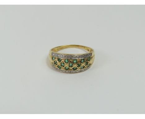 A 14ct gold emerald and diamond dress ring, the emeralds set in three rows across the centre of the band and a row of diamond